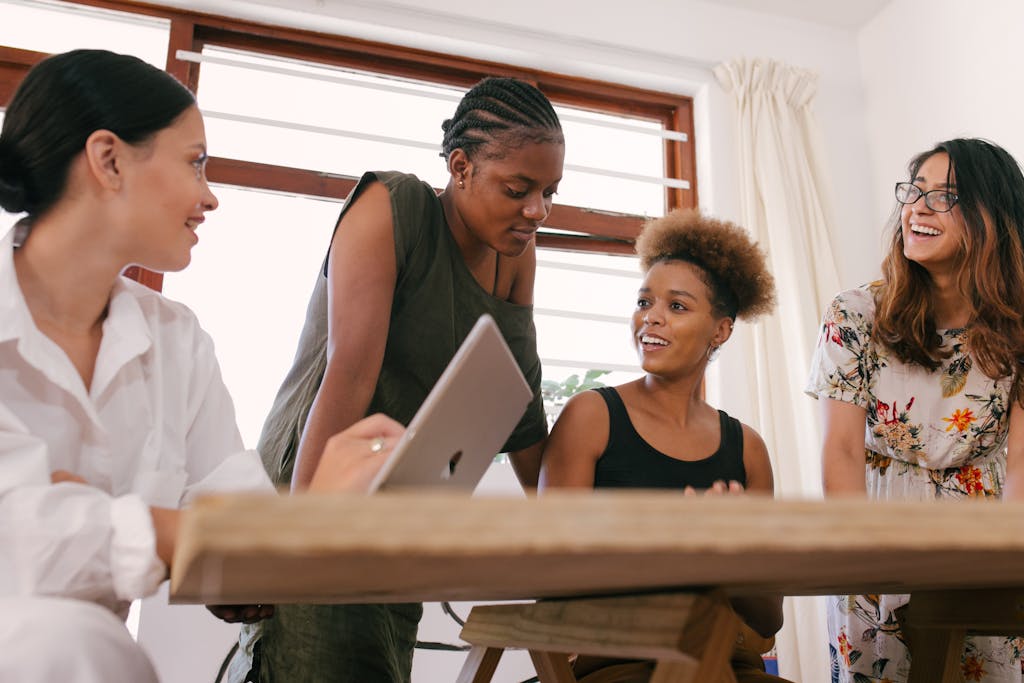 Four women giving main character energy in an office setting engaged in a lively creative discussion.